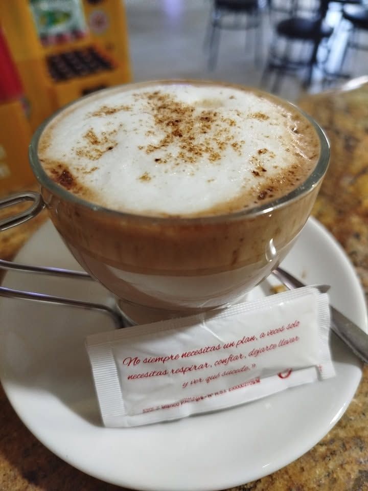Café con leche servido en taza con un sobre de azúcar